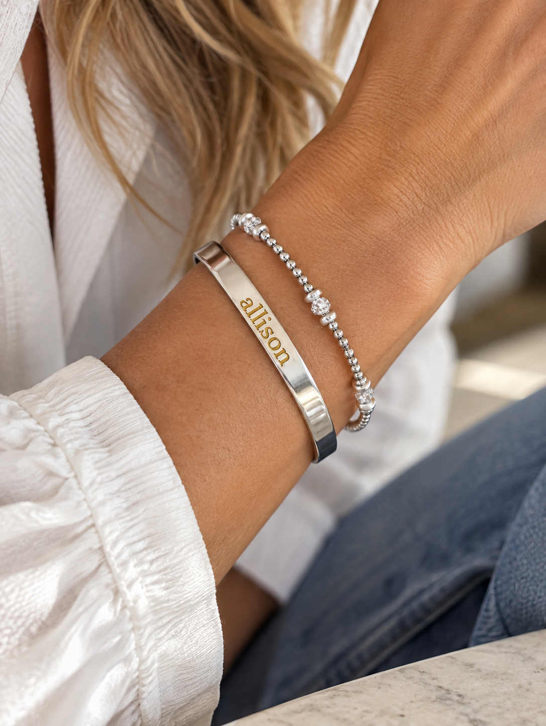 Silver quarter-inch engraved personalized name cuff with gold-filled Allison lettering styled with a silver beaded bracelet