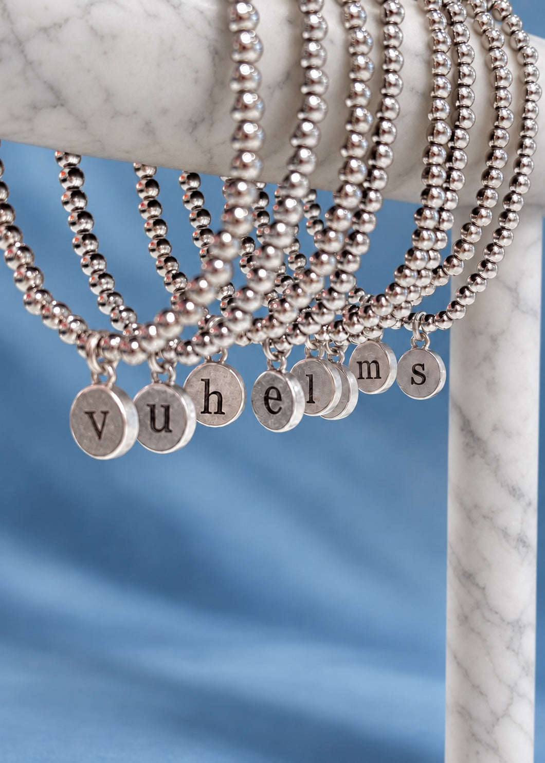 silver initial pendant bracelets on blue background