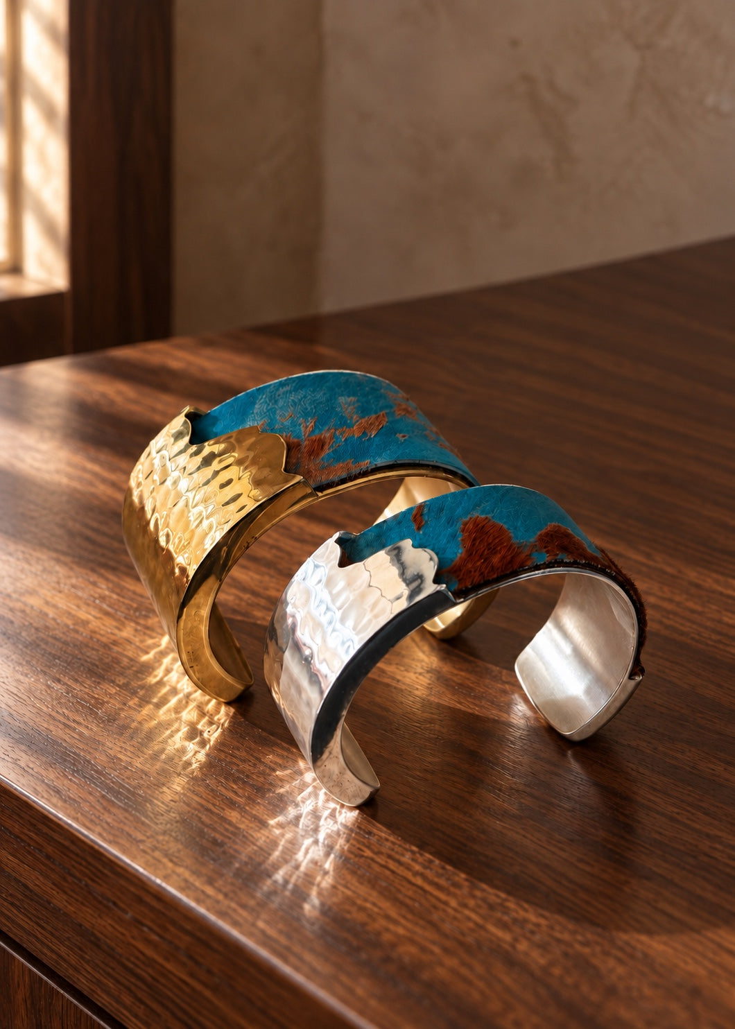 Woodland Blue turquoise Brazilian calfskin Dallas cuffs in gold and silver on a wooden table